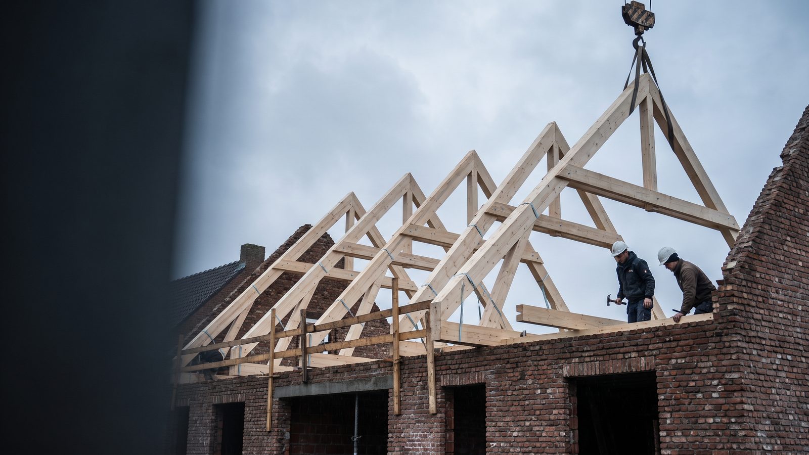 Nieuwe prefab dakspanten op de muurplaat van een Belgische woning, met tijdelijke schoren ertussen