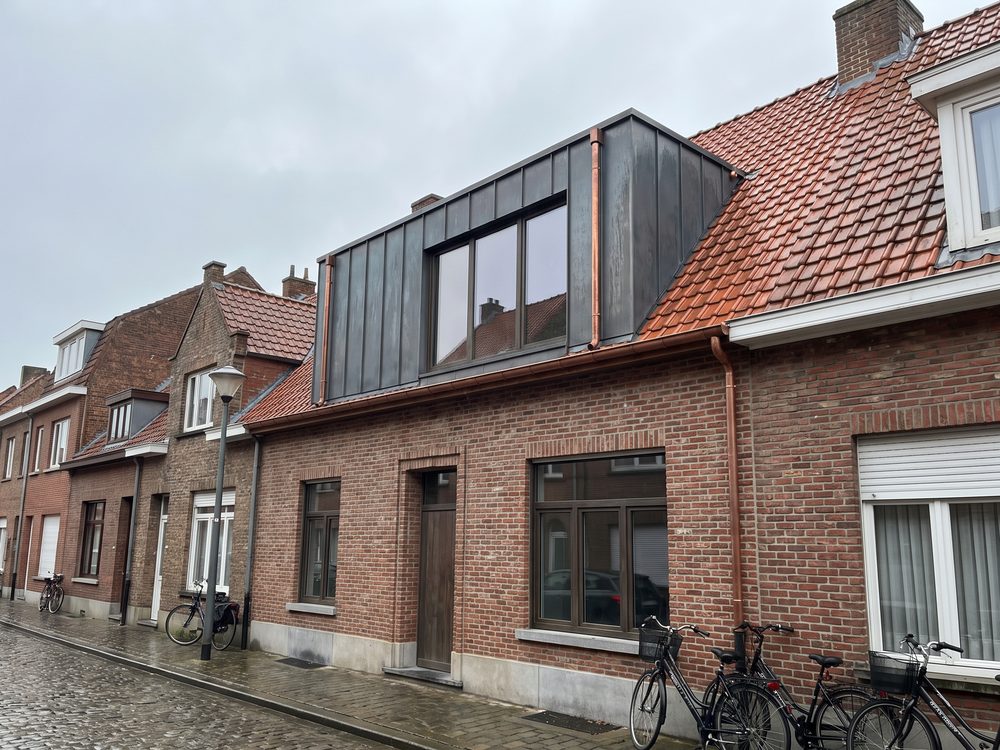 Afgewerkte dakkapel met zinken bekleding in een rood pannendak, gezien vanaf de straat