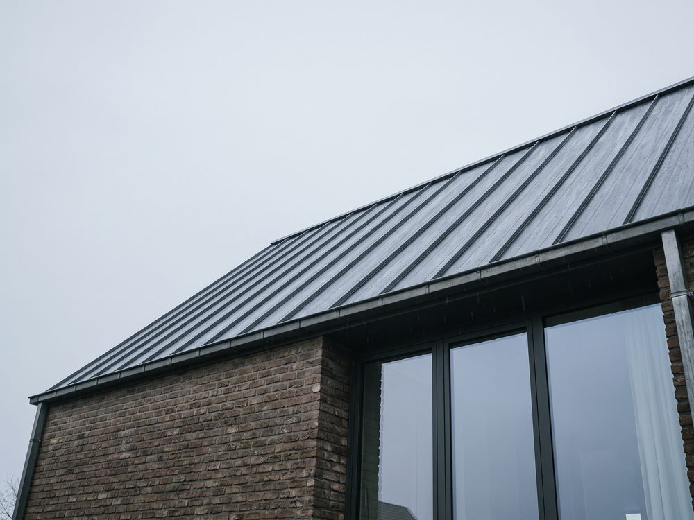 Flauw hellend dak op een moderne uitbouw, afgewerkt met donkere zinken felsbanen