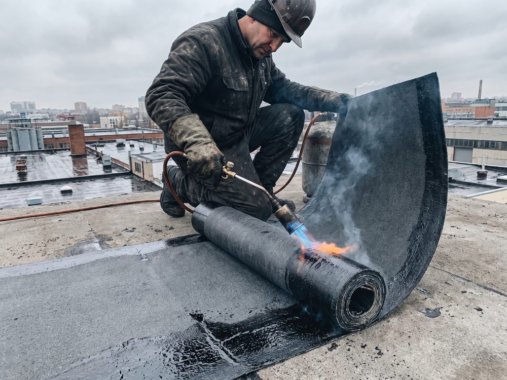 Bitumen roofing wordt met een gasbrander op een plat dak gelegd